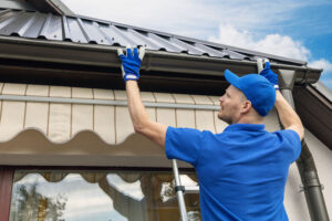 roofing contractor installing gutters on roofing system